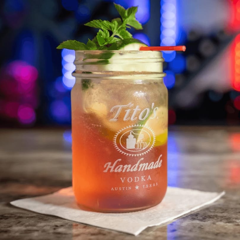 Tito's Handmade Vodka cocktail in a mason jar with mint and a red straw.